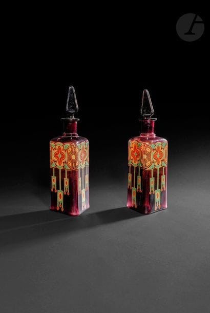 Deux carafes en verre aubergine aux motifs géométriques, Europe pour l’Orient, vers 1925
Panse triangulaire ornée de cercles réunis par des palmettes stylisées à pendentifs perlés. Avec leurs bouchons (l’un accidenté).
Hauteur : 34,5cm

Two glass carafes, Europe for Oriental market, c. 1925
