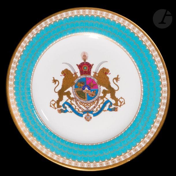 Deux porcelaines, Europe et Iran qâjâr, XIXe - XXe siècle
La première à l’effigie de Nasser ed-Din Shah Qajar (r. 1848-1896) peinte dans un médaillon ovale entouré de compositions florales à l’or et en polychromie sur fond blanc ; la seconde aux armoiries de la cour impériale perse de la dynastie Pahlavi, marli à décor de pétales turquoise. Au dos, texte bilingue anglo-persan mentionnant la commande en 1971 approuvée par Mohammed Reza Pahlavi Aryamehr, pour la commémoration des 2500 ans de la monarchie perse. Édition limitée à 10000 exemplaires. 
Diamètres : 20,5 et 27 cm 
État : sauts de dorure et de polychromie sur la coupelle. 

Two Qajar porcelains, Iran, 19th and 20th century

 La plupart des « Imperial plates of Iran » (assiettes impériales d’Iran) ont été offertes aux chefs d’état et hauts gradés des pays du monde entier. Une majorité a été détruite après la révolution de 1979 en Iran. 