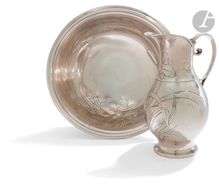 Imposante aiguière de toilette et son bassin en métal argenté, de forme circulaire le bassin et l’aiguière sont ciselés au repoussé de motifs de roseaux, de lys d’eau et de papillons. 
Sans poinçon, époque 1900.
Diamètre du bassin : 44 cm - hauteur : 15 cm
Hauteur de l’aiguière : 35 cm 