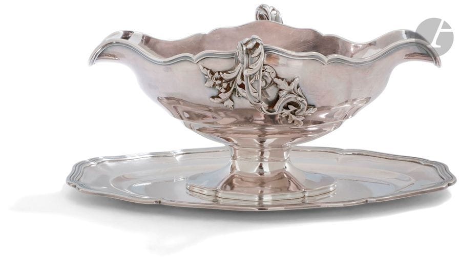 FLAMANT CHAMPENOIS ORFèVRE
Saucière en argent sur son plateau adhérent de forme ovale polylobée mouluré de rangs de filets en rappel sur la saucière, à deux anses feuillagées. 
Poinçon minerve
Poinçon d’orfèvre en toutes lettres
Poids : 630,30 g
Longueur : 24,3 cm - largeur : 15,8 cm
hauteur : 11 cm