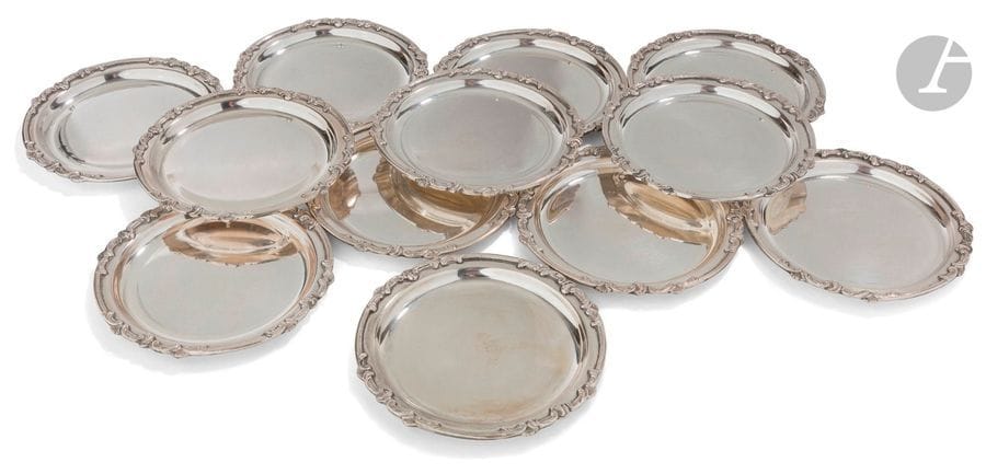 ITALIE TRAVAIL CONTEMPORAIN
Douze dessous de bouteille en argent (800‰) de forme ronde moulurée d’un décor feuillagé espacé. 
Poids : 1043,70 g - diamètre : 12 cm 