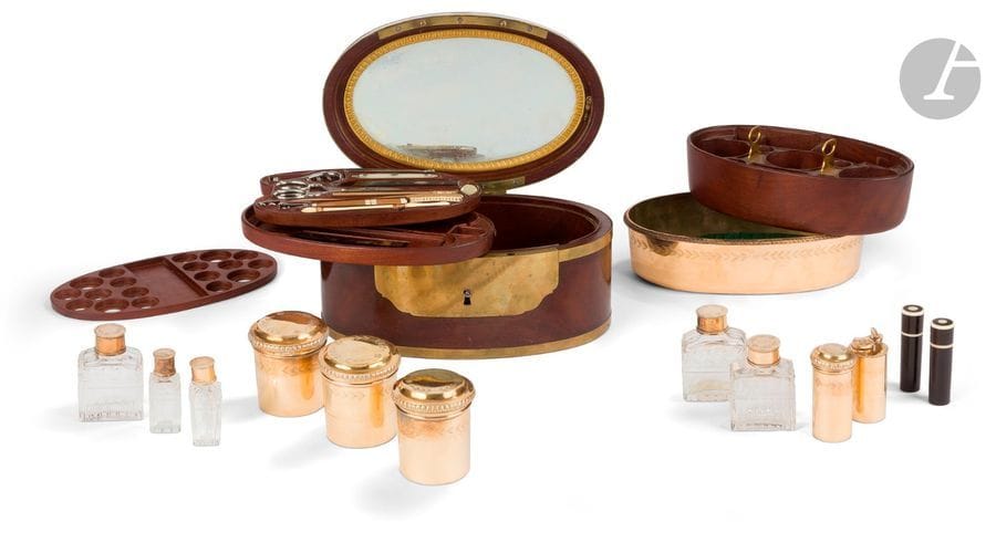 BIENNAIS PARIS 1809 - 1819
Nécessaire de voyage pour homme en vermeil contenu dans son écrin en acajou de forme ovale à la forme du bassin intérieur, contenant sur quatre plateaux en partant du fond : 
- un plateau amovible évidé destiné à recevoir des francs Napoléon (de 20 et 50 francs) 
- une plateau amovible contenant un petit peigne (peigne à poux) 
- une tablette amovible comprenant : une brosse à dents en vermeil, un porte-plume, un couteau pliant double lames argent et acier le manche en nacre, un couteau pliant le manche en écaille la lame en acier, un étui à aiguilles en ivoire, un accroche miroir en acier, un tire-bouchon pliant en acier, deux paires de ciseaux superposés, un étui à aiguilles en ivoire et bois, une pince à épiler en acier, une vrille la prise en nacre, 
- un bassin en vermeil de forme ovale mouluré de feuilles d’eau et ciselé d’un rang de feuilles sur le pourtour, dans lequel vient s’insérer un élément en bois recevant : deux boîtes à pommade circulaires, une boîte à savon et à éponge, un encrier et sa boîte à sels dévissable, un étui à blaireau, deux étuis oblongs en ivoire et cinq flacons en cristal taillé et leurs bouchons en vermeil. 
Au revers du couvercle figure un miroir à suspendre de forme ovale. 
État : manquent deux peignes en écaille, un dé en vermeil et la clé tréflée d’entrée de serrure, accident au col d’un des petits flacons. 
Poinçons au deuxième coq (Paris 1809 - 1819), poinçon d’orfèvre et en toutes lettres BIENNAIS au revers du bassin, poinçon de garantie des orfèvres. 
Poids : 786,80 g - longueur : 22,6 cm largeur : 14,2 cm - hauteur : 11,6 cm 
Deux nécessaires identiques sont exposés au Musée Napoléonien de Rome.