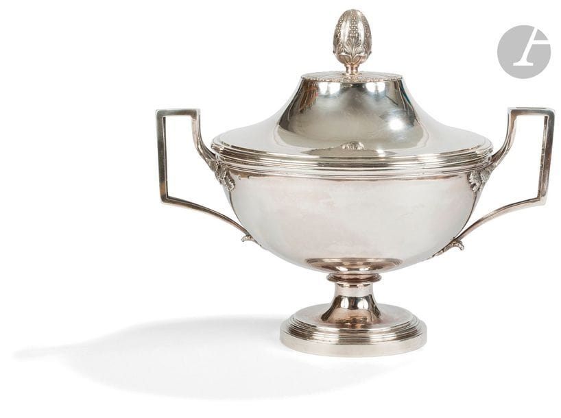 PARIS 1798 - 1809
 Soupière en argent reposant sur un piédouche à gradins, les anses à la grecque et un couvercle sommé d’une pomme de pin sur une terrasse feuillagée amovible. 
Orfèvre : corps de la soupière : François SICARD, biffé en 1808
Couvercle postérieur poinçonné à la minerve, orfèvre différent. 
Poids net : 1665,80 g - hauteur : 26 cm
diamètre avec les anses : 31,7 cm
