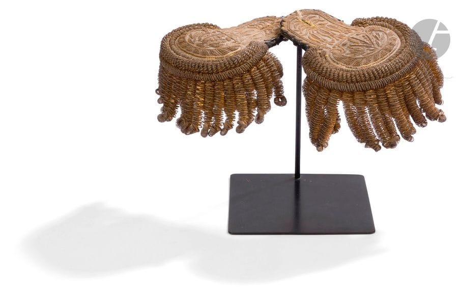 Paire d’épaulettes attribuée à un officier supérieur d’état-major. 
Corps brodés de feuilles de chêne et de laurier, de feuillages en canetille et paillettes dorées. Triple tournante et frange à grosses torsades en passementerie dorée. Doublure postérieure en rayonne.
Avec support de présentation. 
B.E. (À nettoyer). Époque Restauration. 