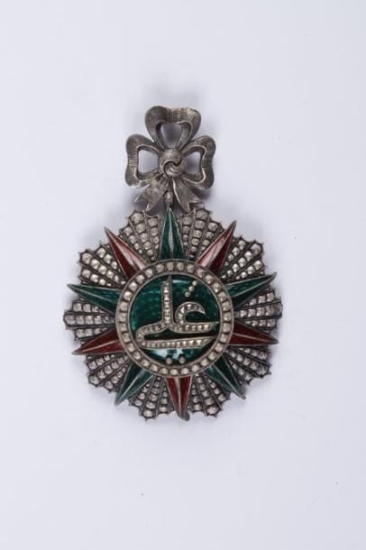 TUNISIE
Ordre du Nichan Iftikar Ali-Bey (1882-1902). Etoile de commandeur en argent ciselé émaillé. Pastille de la maison Lemaitre à Paris. Plusieurs pointes de l'étoile faussé. Manque l'anneau de suspension de la cravate. T.B.