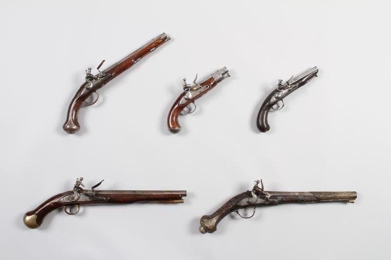 Pistolet à silex d'Officier de Marine. Canon rond à pans au tonnerre. Platine signée « A Tulle » et chien col de cygne à corps rond. Garnitures en fer découpé. Crosse en noyer, sculptée d'une fleur et d'une tête de chien de Mer. Baguette en fer. A.B.E. Vers 1770-1780.