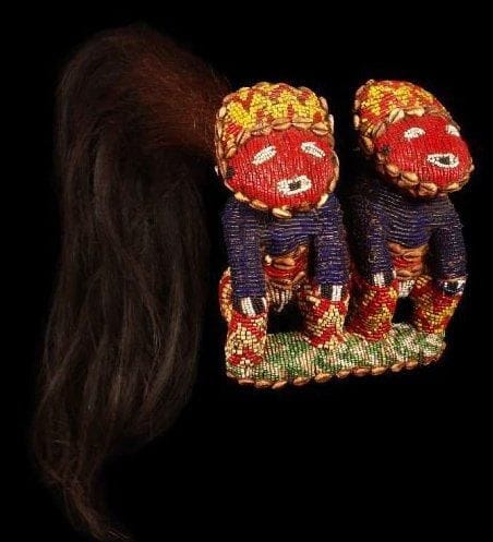 Fouet de danse BAMOUM (Cameroun). Manche en bois gainé de perles granulaires arrangées en chevrons, terminé d'un côté par une queue en crins de cheval, de l'autre par une sculpture représentant des jumeaux, entièrement décorée de perles multicolores et de cauris. Faisant partie des objets de luxe, ils sont destinés à affirmer le prestige des «Fon» et de leurs notables.. Longueur: 61 cm.