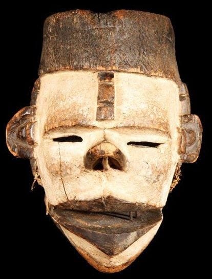 Masque OGONI (Nigéria). Petit masque au visage peint au kaolin, la mâchoire inférieure articulée, révélant à l'ouverture de fines dents formées de baguettes de bois. La bouche en losange, le nez recourbé, la coiffure et les tatouages de teinte noire. Elégant masque de belle ancienneté.. Hauteur:18 cm.