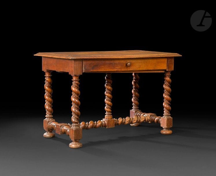 Table en noyer avec tiroir en ceinture, piètement torsadé avec entretoise en H supportant une colonnette, plateau bordé d’un bec de corbin, pieds en boules aplaties.
Val de Loire, fin du XVIIe/Début du XVIIIe siècle
Hauteur : 77 cm - Longueur : 121 cm 
Profondeur : 67.5 cm
(vermoulures, restaurations d’usage)