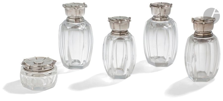 TéTARD FRèRES et BACCARAT
Garniture de toilette en cristal et argent composé de quatre flacons et d’un pot à pommade, le corps de forme hexagonale en rappel sur les bouchons à vis en argent moulurés de perles. 
Poids brut : 1794,30 g