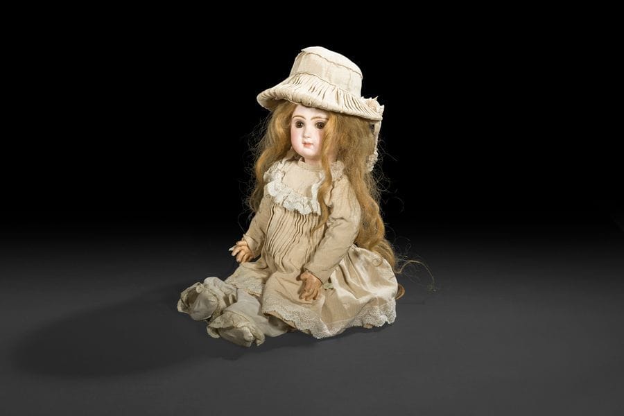 Bébé JUMEAU, tête en porcelaine marquée au tampon rouge : Déposé Tête JUMEAU Bté S.G.D.G, T.9, (léger défaut en haut de la tête sous la perruque), yeux fixes bruns, bouche fermée, oreilles percées, perruque blonde. Corps articulé en bois et composition, étiquette bleue : Bébé JUMEAU Diplôme d’honneur, robe crème à volants de dentelle et chapeau assorti.
H : 54 cm