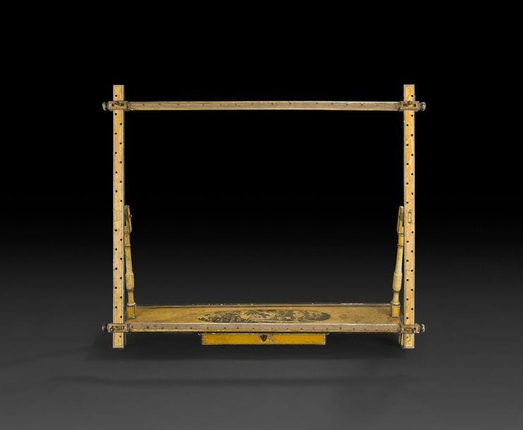 Métier à tisser en bois peint en camaïeu gris sur fond jaune, à deux montants en balustre et châssis basculant, reposant sur une plateforme ouvrant à un tiroir à décor d’un paysage de chaumières au bord d’une rivière.
Début du XIXe siècle (accidents et manques).
H (approx.) : 70 cm, L : 79 cm