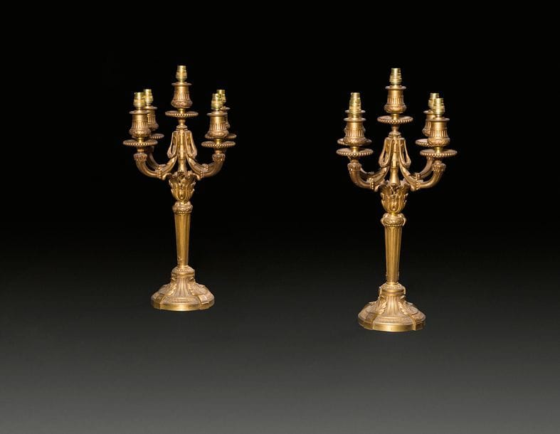 Paire de candélabres en bronze doré à quatre lumières, le fût à cannelures reposant sur une base circulaire à canaux, feuillages et rais de cœurs ; (montés à l’électricité).
Style Louis XVI, fin du XIXe siècle.
H : 45 cm