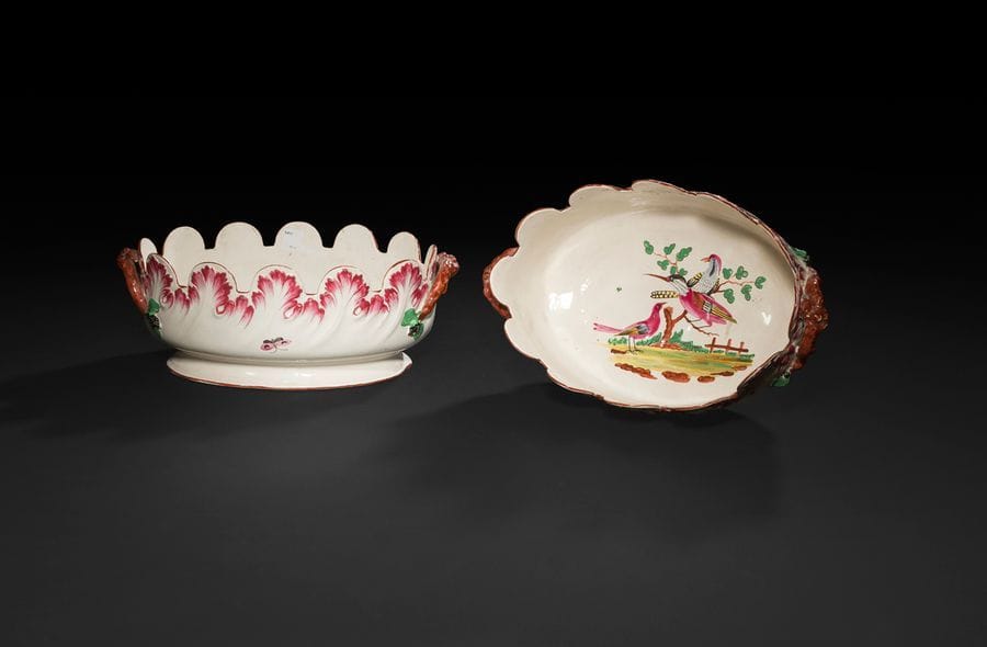 Lunéville
Paire de verrières ovales crénelées en faïence, les créneaux ornés de feuilles d’acanthe en relief rehaussées de peignés pourpre, les anses en forme de branches et feuillage au naturel, à décor polychrome au centre d’oiseaux sur un arbuste sur terrasse.
XVIIIe siècle. 
(Un créneau restauré).
L : 30,5 cm