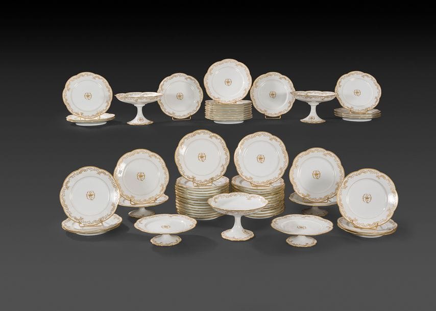 Paris
Partie de service en porcelaine à décor en or et rouge du monogramme CO encadrant une couronne comprenant 61 assiettes plates, quinze assiettes à potage.
On y joint 53 assiettes et 7 présentoirs d’un autre modèle.
Fin du XIXe siècle. 
(Quelques éclats).