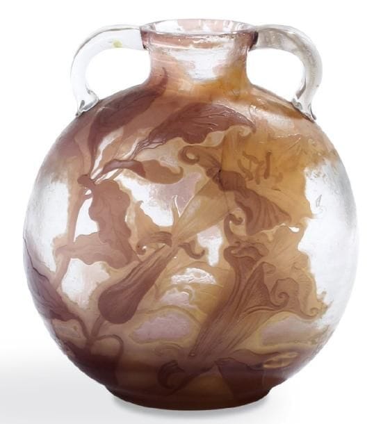Émile GALLE (1846-1904)
Important vase gourde à panse aplatie et à deux anses appliquées et modelées à chaud. Étude en verre soufflé multicouche dégagé à l'acide à décor, parme, beige et mauve dégradé, de brugmansias sur fond translucide légèrement marbré. Vers 1900. Signature gravée en camée à l'acide et mention Étude gravée. Hauteur: 29 cm. Fêlure démarrant au col et se poursuivant jusqu'à la moitié de la panse.