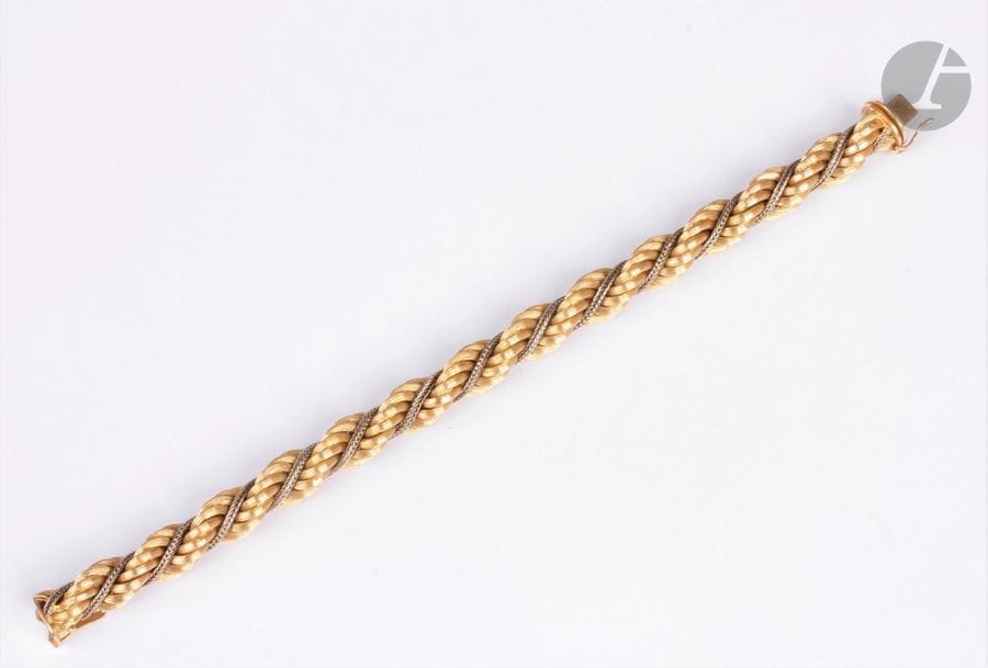 Bracelet torsadé en or jaune 18K (750) strié et cordelette d'or gris 18K. Longueur : 20,5 cm environ. Poids : 40,2 g