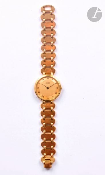 EMERICH MEERSON Vers 1990 
Montre bracelet pour femme en or jaune 18K (750), cadran guilloché doré, index chiffres romains formant les heures, mouvement à quartz, bracelet en or jaune 18K intégré.
Cadran, boîtier signés.
Diamètre : 29 mm  -  longueur : 17,5 cm
Poids brut : 66 gr