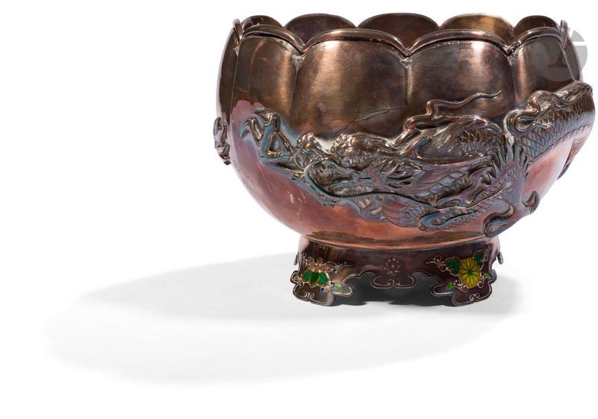 JAPON - Époque MEIJI (1868 - 1912)
Bol à aumônes en forme de lotus en argent à décor en relief d’un dragon à trois griffes reposant sur un pied quadripode orné en émail polychrome de fleurs de kiku et de paulownia. Signé Tokosai Setsuga. (Dépatiné, rayures). 
Diam. 17,4 cm ; poids brut : 849 g