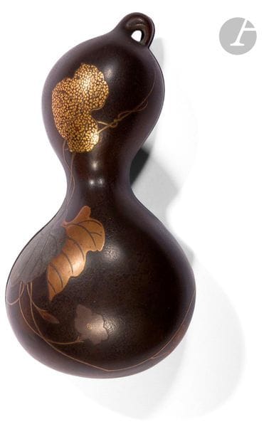 JAPON - Époque MEIJI (1868 - 1912)
Boîte de forme double gourde en laque brun à décor en hira maki-e de laque or, argent, brun et kirigane de branches de feuilles et fleurs. (Petites égrenures en bordure). 
L. 18 cm ; poids : 286 g