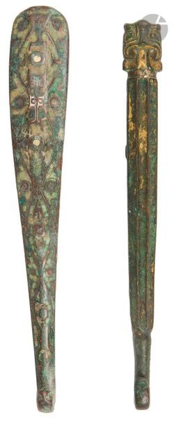 CHINE - Époque HAN (206 av. JC - 220 ap. JC)
Deux fibules en bronze à trace de dorure, la tête de l’une forme taotie. 
L. 17,5 et 18,3 cm