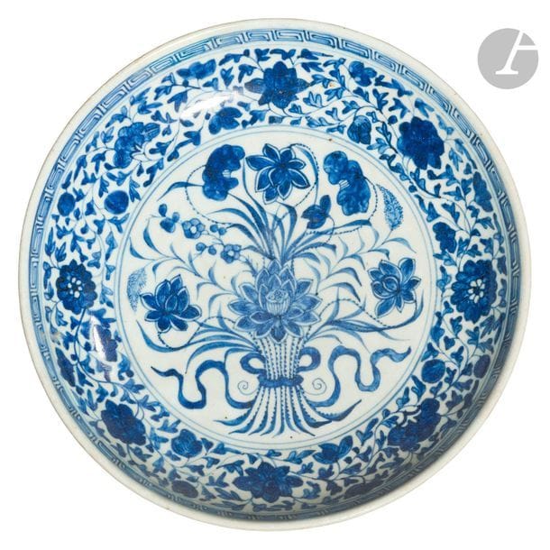 CHINE - XVIIIe siècle
Plat creux en porcelaine blanche émaillée en bleu sous couverte dans un médaillon central d’un bouquet de fleurs de lotus épanouies, de frises de fleurs dans leurs rinceaux feuillagés en réserve, de grecques en bordure. (Restauration en bordure).
Diam. 27,9 cm