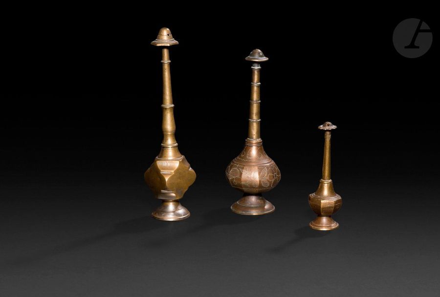 Lot de trois aspersoirs, Inde, XIXe siècle
En alliage cuivreux, sur pied circulaire et à embout bulbeux perforé. Le petit à fût cylindrique et panse à huit pans coupés, le moyen à fût cylindrique annelé et panse piriforme nervurée à décor gravé de lignes en points, le plus grand à fût galbé et panse polyédrique. 
Hauteur : de 11 à 21 cm

Three Indian sprinklers, 19th century