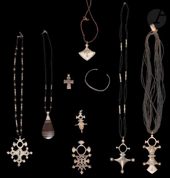 Neuf bijoux sud-sahariens, Touareg, XXe siècle
Argent et alliage cuivreux et colliers de perles de verroterie noire ou liens en cuir. 6 croix du Niger tanayilt à décors incisés géométriques dont une croix d’Abalak, une de Bartchakea ; un pendentif dit talhakim, un pendentif en « goutte » en ébène, un pendentif en forme de croix et un bracelet rigide.
De 3,5 à 10 cm 
Poids brut : 218 g

Bibliographie :
V. Beltrami, Croix d’Agadez, Encyclopédie berbère, 14 | 1994, 2129-2133 ; A. Durou, Bijoux nomades : le paysage aux sources de l’inspiration, Genève, Aubanel, 2006.

9 pieces of Tuareg jewellery, 20th century