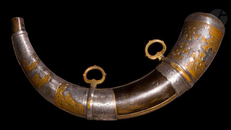 Poire à poudre, Maroc, fin XIXe siècle
Poire à poudre en corne garnie de plaques de métal argenté et de laiton découpées et ciselées de volutes et de motifs végétaux. Munie de deux anneaux de suspension. 
Longueur : 33 cm 
État : corde et chaînette du bouchon manquantes, une extrémité cabossée.

A horn powder flask, Morocco, late 19th century.