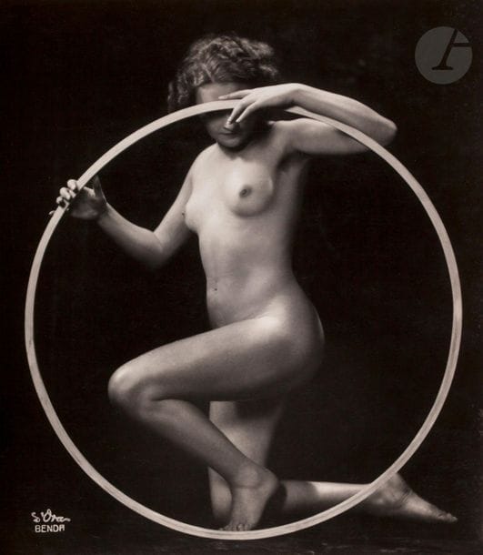 Dora Kallmus - Arthur Benda 
Nu au cerceau, c. 1925-1935. 
Épreuve argentique d’époque. Signature du photographe dans le négatif. Tampon « Copyright d’Ora - Wien, 1 - Arthur Benda » et étiquette du studio au verso. 
19 x 16,5 cm

Dora Kallmus - Arthur Benda
Nude with a hoop, c. 1925-1935.
Vintage gelatin silver print. Photographer's signature on the negative. Stamp "Copyright d'Ora - Wien, 1 - Arthur Benda" and studio label on verso.
19 x 16.5 cm