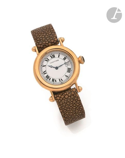 CARTIER DIABLO. Vers 1990
N° R 1426
Montre bracelet pour femme en or jaune 18K (750), cadran blanc, index chiffres romains formant les heures, date par guichet à 3h, mouvement à quartz (fonctionne), bracelet galuchat (déchiré) avec sa boucle déployante en or 18K signée.
Cadran, boîtier et mouvement signés.
Diamètre : 32 mm
Poids brut : 54,3 g