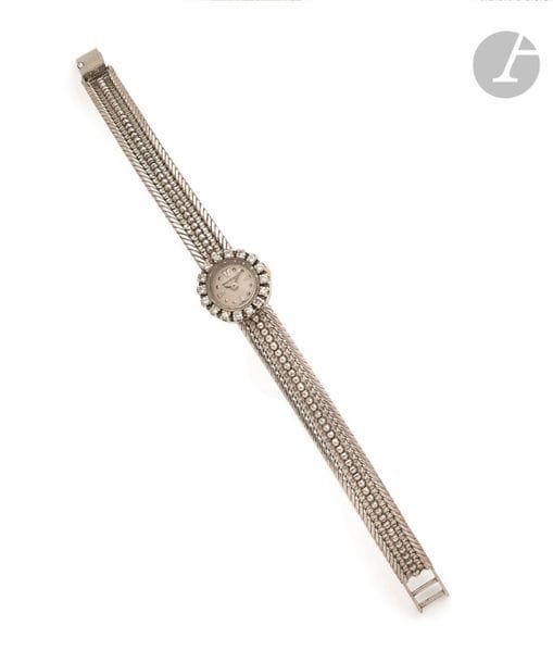JAEGER LECOULTRE. Vers 1960
N° 151935
Montre bracelet pour femme en or gris 18K (750), lunette sertie de diamants taille brillant, cadran blanc, index appliqués formant les heures, mouvement à remontage mécanique, bracelet en or gris 18K. 
Cadran, boîtier et mouvement signés. 
Longueur : 16 cm
Poids brut : 22,9 g