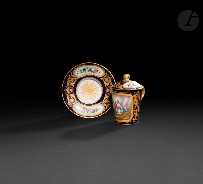 Sèvres (genre de)

Tasse couverte et sa soucoupe enfoncée dite trembleuse en porcelaine à décor polychrome d'une scène galante dans le style de Boucher dans un réserve sur fond bleu orné de rinceaux feuillagés en or, le couvercle et la soucoupe décorés de bouquets de fleurs.

Marque apocryphe de Sèvres.

Seconde moitié du XIXe siècle.

H : 14 cm