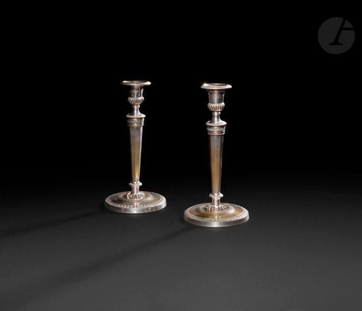 Paire de flambeaux en métal plaqué dans le goût de Claude Galle, le fût à pan reposant sur des griffes, la base circulaire à décor guilloché.

XIXe siècle.

H : 25 cm