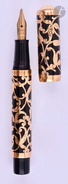 Stylo plume eyedropper en or 18 carats, travail anglais. Ebonite noire avec un habillage filigree et laque noire. Plume or 18 carats, remplissage compte-gouttes. Petits coups et micro-rayures.
Longueur : 100 mm - Poids brut : 16 g