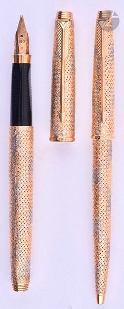 BOUCHERON
Parure stylo plume et stylo bille en or 18 carats tressé deux ors. Réalisée sur une base de Parker 75. Plume or 18 carats, remplissage cartouche. Bille avec capuchon poussoir. Micro-rayures. 
Longueur du plume : 129 mm - Poids brut de la parure : 50 g