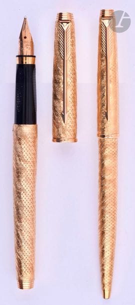 BOUCHERON
Parure stylo plume et stylo bille en or 18 carats tressé puis gravé avec un décor moiré. Réalisée sur une base de Parker 75. Plume or 18 carats, remplissage cartouche. Bille avec capuchon poussoir. Micro-rayures. 
Longueur du plume : 129 mm - Poids brut de la parure : 50 g