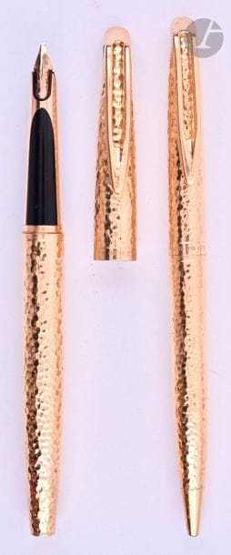 CARTIER
Parure stylo plume + stylo bille en or 18 carats décor martelé. Sur une base de Waterman CF. Réalisé par le joaillier parisien Lefebvre. Plume or 18 carats, remplissage par convertor. Système bille par quart de tour. Micro-rayures. 
Longueur : 134 mm - Poids brut : 76 g
