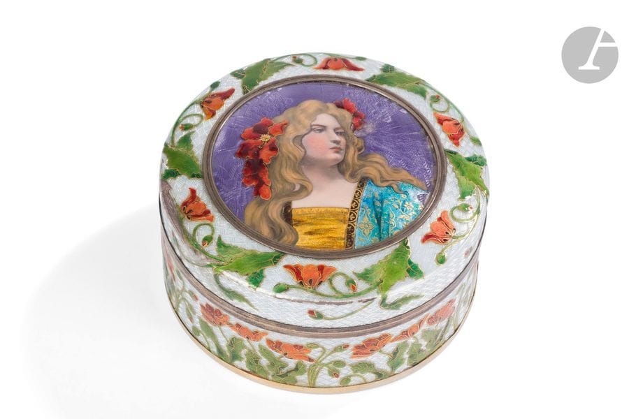 TRAVAIL ART NOUVEAU 
Jeune fille aux coquelicots 
Boîte circulaire en laiton, les décors réalisés aux émaux polychromes, translucides et à l’or sur fond guilloché. Accidents, chocs et manques épars aux parties émaillées. H. 7 cm – D. 13,5 cm 
