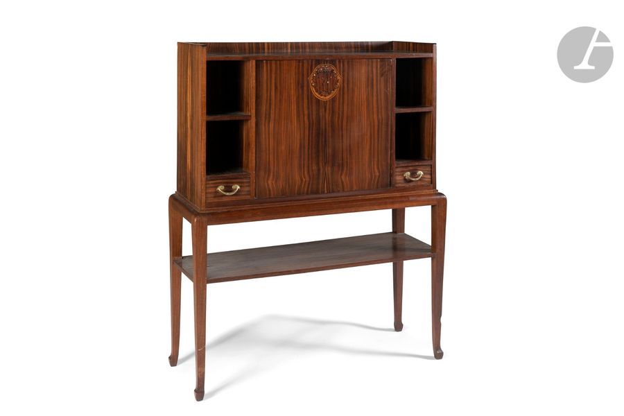 LOUIS MAJORELLE (1859-1926)
Cabinet en palissandre et placage d’ébène de Macassar. Le corps suspendu s’ouvre par un abattant central, au motif décoratif réalisé en marqueterie, encadré latéralement par des niches recevant, chacune, un tiroir en partie basse et une tablette au centre. Prises en bronze d’origine. La base, aux pieds d’angle mouvementés, accueille une tablette d’entrejambe. Circa 1920. Une brûlure sur l’arête de l’un des pieds, fendillements épars au pacage, état d’usage. Signé à la coquille MAJORELLE en marqueterie sur un côté. 
H. 125 cm – L. 98 cm – P. 38 cm