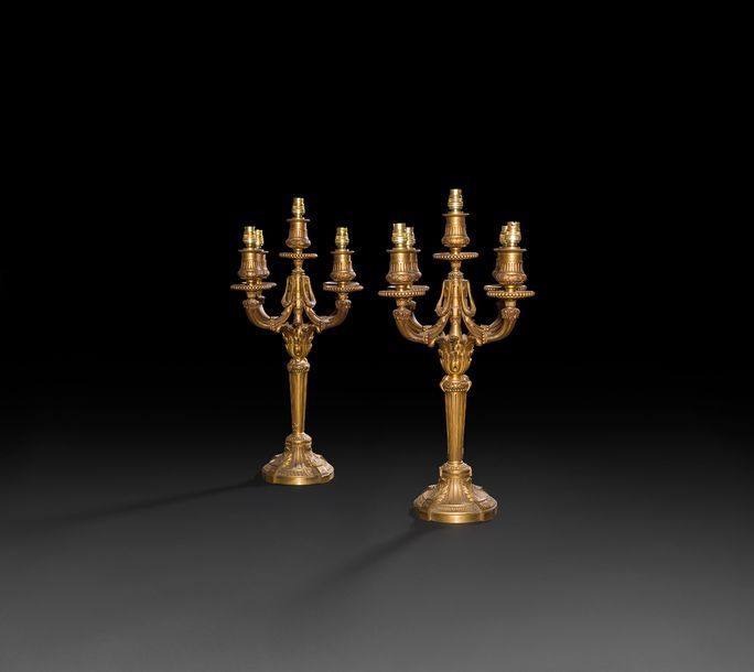 Paire de candélabres en bronze doré à quatre lumières, le fût à cannelures reposant sur une base circulaire à canaux, feuillages et rais de cœurs ; (montés à l'électricité).

Style Louis XVI, fin du XIXe siècle.

H : 45 cm