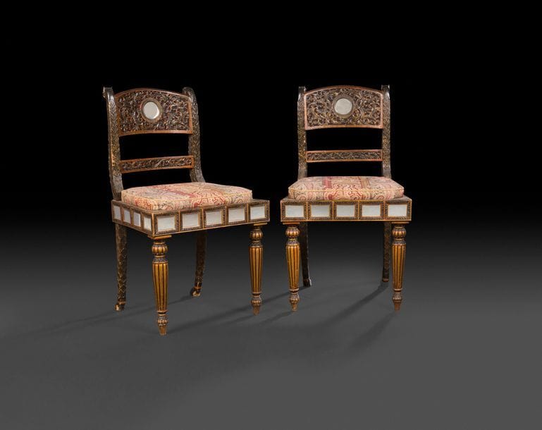 Paire de chaises en bois sculpté et peint en rouge noir et or, le dossier ajouré à rinceaux flanqué de têtes de lionnes à l'arrière, la ceinture à plaques de miroirs reposant sur des pieds en balustres.

Inde, XIXe siècle.

H : 94 cm, L : 53,5 cm