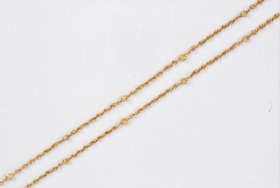 CHANEL
Sautoir fantaisie en métal doré articulé de maillons enchevêtrés et de perles dorées. Signé. Longueur : 186 cm environ