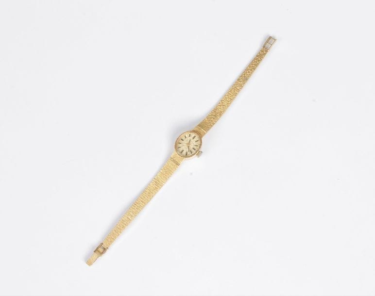 Montre de dame en or 18K (750), cadran ovale, bracelet ruban en or 18K satiné, mouvement mécanique. Longueur : 16,5 cm environ. Poids brut : 23,7 g (accident, remontoir en métal)