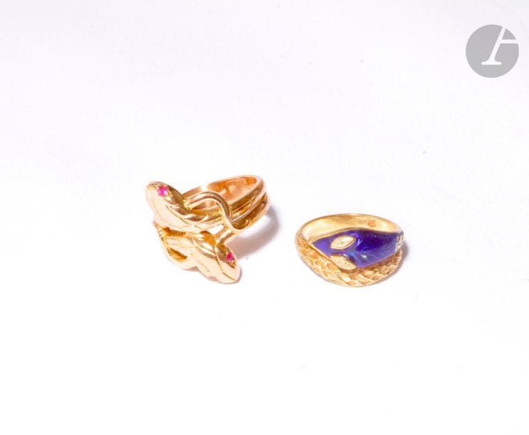 Lot de deux bagues serpents en or 18K (750), l’une agrémentée de pâtes de verre rouges, la seconde à décor émaillé. Poids brut : 14,6 g (manque à l’émail)