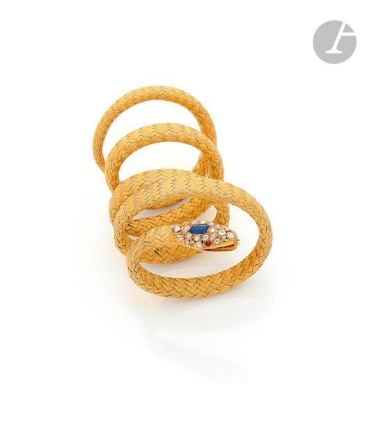 Bracelet armille en or jaune 18K (750) tressé dessinant un serpent, la tête ornée d’un saphir quadrangulaire, sertie de diamants taillés en roses, les yeux piqués de rubis. Travail du début du XXe siècle. Dimensions : 68 x 0,9 cm. Poids brut : 52,4 g (déformations, égrisures)
 L’armille est connu depuis l’Antiquité, chez les Romains par exemple où il était considéré comme un emblème de bravoure militaire et offert à titre honorifique. L’armille se distingue du bracelet car il se porte haut sur le bras et se présente sous la forme d’une spirale très souvent serpentiforme pouvant s’adapter facilement. Le serpent sera repris beaucoup plus tard et très à la mode au XIXe siècle, début du XXe siècle. Le bracelet que nous proposons représente un tour de force technique mettant au défi la souplesse d’un motif à la résistance d’une utilisation.
