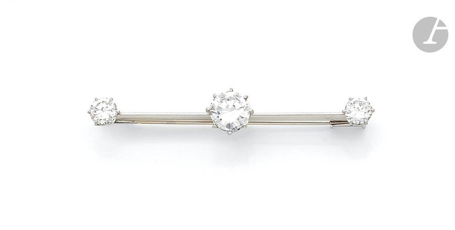 Broche-barrette en platine et en or gris 18K (750), sertie d’un diamant rond de taille brillant pesant 1,76 ct, les extrémités ornées chacune d’un diamant rond demi-taille. Travail français. Longueur : 5,2 cm environ. Poids brut : 6,2 g

Le diamant pesant 1,76 ct accompagné d’un rapport LFG attestant : couleur E, pureté SI1
