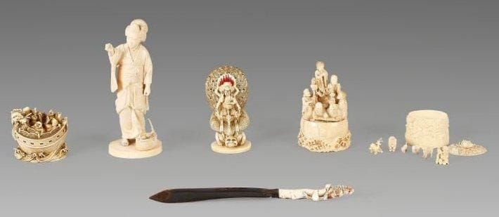 Okimono en ivoire, jeune femme debout vêtue d'un kimono, la main droite levée, portant dans sa main gauche un panier rempli de coquillages. Japon, XIXe siècle. (Accidents et manques). Hauteur: 19 cm.