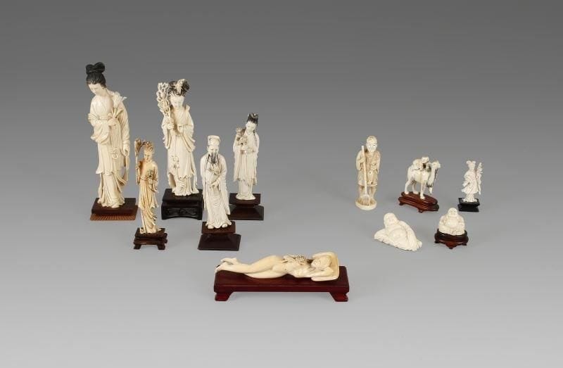 Statuette de jeune femme dite «médecin» en ivoire, la tête posée sur un oreiller et reposant sur son bras gauche replié et tenant de l'autre main une pivoine. Chine, XXe siècle. Largeur: 17 cm.