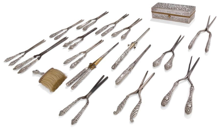 Étonnante collection de seize fers à friser les manches en argent à décor repoussé pour la plupart de motifs feuillagés et enroulements, une boîte rectangulaire à chauffer les fers en laiton recouvert d'argent et une petite brosse en crins et manche argent.

Angleterre, villes de Londres et Birmingham, fin du XIXe siècle, début du XXe (plusieurs lettres-date et différents orfèvres).

Poids brut : 1906 g
